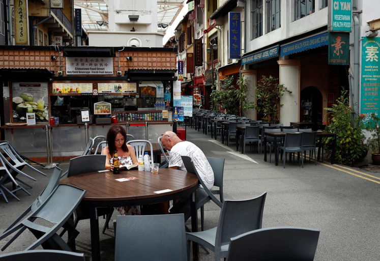 Tourists sit at a table at a largely empty Chinatown district as tourism takes a decline due to the coronavirus outbreak in Singapore February 21, 2020. Picture taken February 21, 2020. 