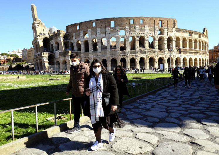 Tourists wearing a protective respiratory mask tour outside the Colosseo monument (Colisee, Coliseum) in downtown Rome on February 28, 2020 amid fear of Covid-19 epidemic. 