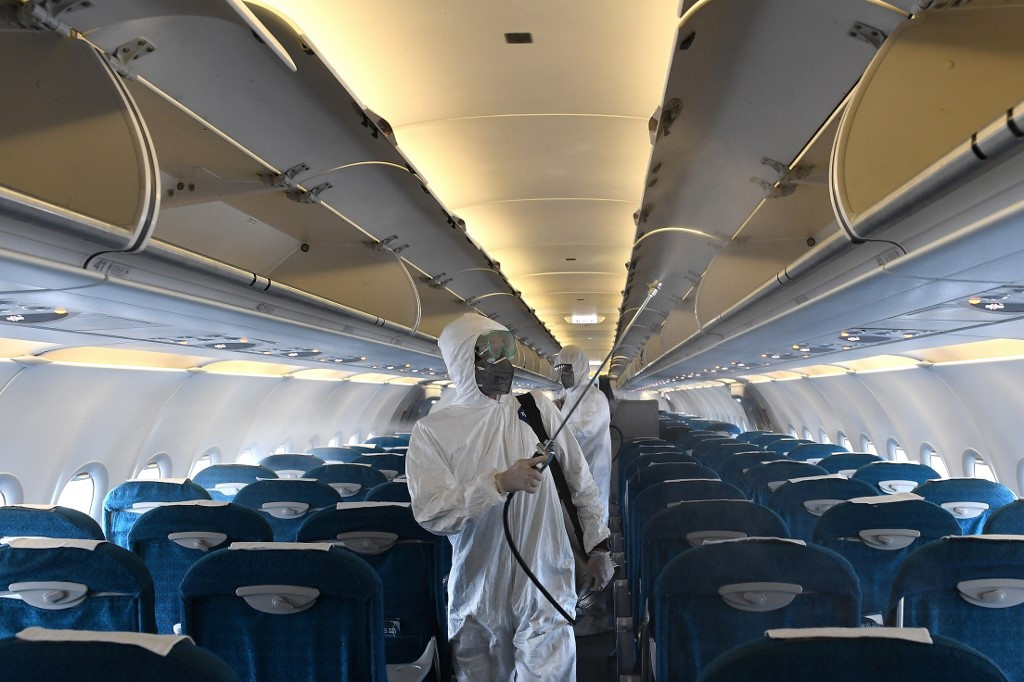 Workers wearing protective suits disinfect a Vietnam Airlines plane at Noi Bai International Airport in Hanoi on March 3.