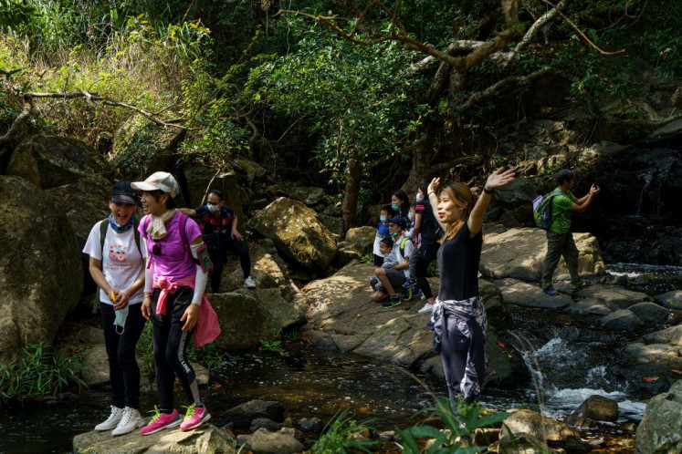 In this picture taken on March 1, 2020, people stop for a break on a hiking trail near a waterfall in the Tseung Kwan O area of Hong Kong. 
