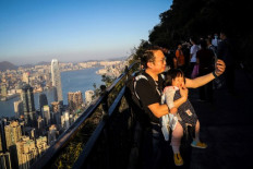 In this picture taken on Feb. 22, 2020, a man takes a selfie with his baby along a hiking trail. Remote hiking trails are offering Hong Kongers an open-air escape from the coronavirus fears that have engulfed the densely-populated city and triggered the closure of public facilities and schools. 