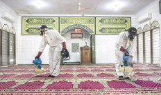 Workers from the Indonesian Mosque Council spray disinfectant on carpet at Hablul Muttaqin Mosque on Jl. Pejambon in Central Jakarta on Friday.