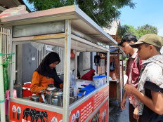 Fitri Ramandani, a 17-year-old Thai tea vendor, serves customers  in Kayu Putih district in East Jakarta on Friday. 
