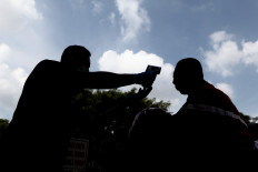 Member of presidential Security Detail (Paspampres) check on a visitor's body temperature using a thermal Gun at the Presidential Palace in Jakarta, on March 3, 2020. spread of the corona virus.

