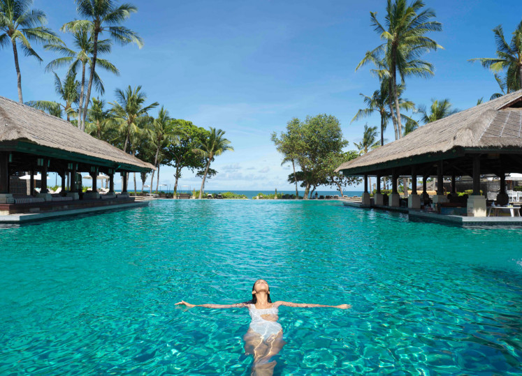 Float back and relax: A woman is seen swimming in a large pool facing the ocean beachside, at the Intercontinental Bali Resort in Bali, in this undated picture.