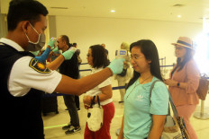 An Indonesian health official takes the temperatures of arriving passengers at I Gusti Ngurah Rai Airport, Bali, on March 10.