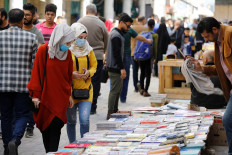 Iraqi women wear protective face masks, following an outbreak of coronavirus, as they look at books at Mutanabbi Street in Baghdad, Iraq, on March 6, 2020. 