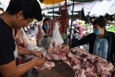 Shoppers wear face masks on March 14, 2020, as they choose cuts of pork at a fresh meat vendor at a market in Phnom Penh during the COVID-19 pandemic.