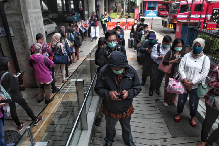 Passengers line up to enter Lebak Bulus MRT Station in Jakarta, on Monday. The Jakarta administration reduced the operations of city-operated public transportation to reduce the spread of the Covid-19 virus.
