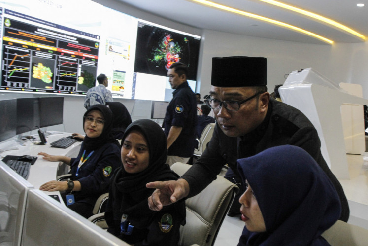 West Java Governor Ridwan Kamil (second right) looks over  pandemic data at the COVID-19 Information and Coordination Center on March 10, 2020, in Bandung, West Java.