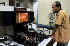 Quality control: Preservation technician Budi watches a cleaned movie reel looking for defects. JP/Xena Olivia
