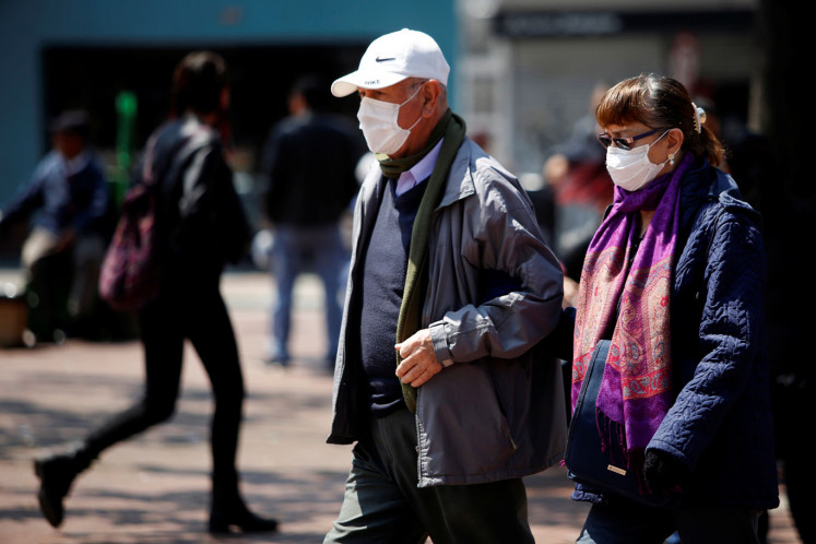 People walk on the street, wearing protective masks as a preventive measure against the spread of the coronavirus disease (COVID-19), in Bogota, Colombia March 17, 2020. 