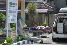 A medical officer brings a patient inside the Central General Hospital H Adam Malik Medan, in Medan, North Sumatra, on March 18, 2020.