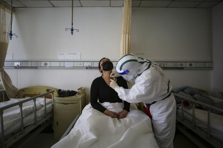 A patient (L) infected by the COVID-19 coronavirus receives acupuncture treatment at Red Cross Hospital in Wuhan in China's central Hubei province on March 11, 2020.