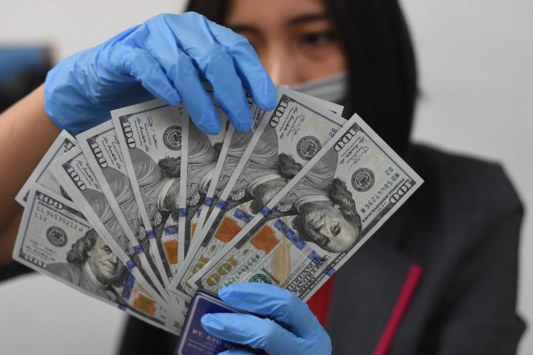 A clerk arranges US dollar bills at a foreign currency exchange outlet in Jakarta in March 2020.