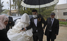 Palestinian groom Imad Sharaf, wearing gloves and a face mask, accompanies his bride Bara'a Amarneh as they arrive at their home in the village of al-Dahriya, south of Hebron in the West Bank, on March 20, 2020. 