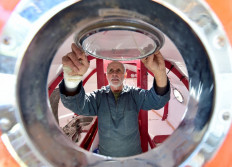 In this file photo taken on November 15, 2018 Jean-Jacques Savin, 71, a former paratrooper, works on the construction of a ship made from a barrel at the shipyard in Ares, southwestern France. 