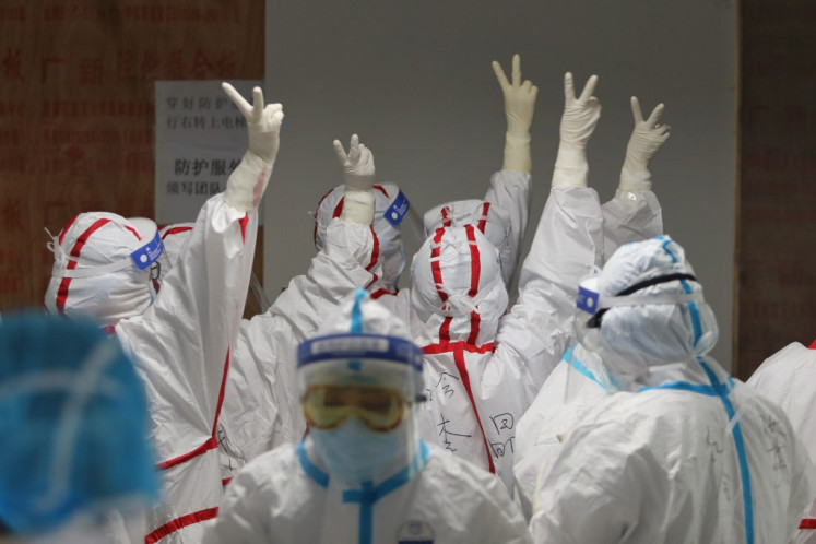 Medical staff cheer themselves up before going into an ICU ward for COVID-19 coronavirus patients at the Red Cross Hospital in Wuhan in China's central Hubei province on March 16, 2020.  China reported 12 more imported cases of the novel coronavirus on March 16 as the capital tightened quarantine measures for international arrivals to prevent a new wave of infections.  