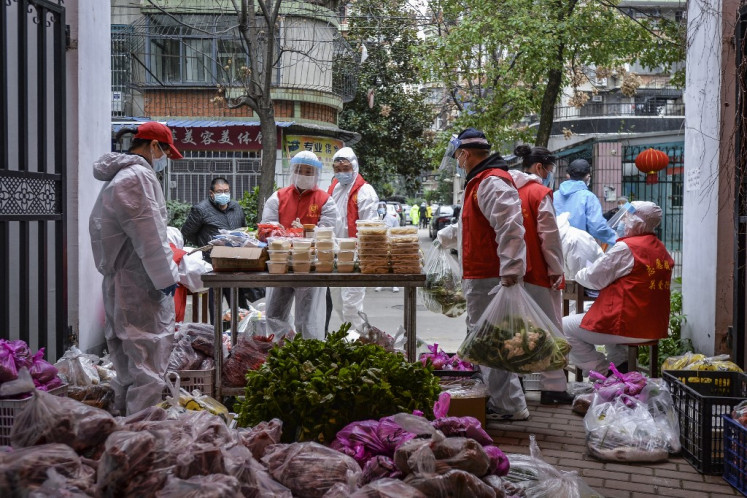 This photo taken on March 16, 2020 shows community volunteers distributing foods ordered by residents in Wuhan, China's central Hubei province. - China reported on March 17 just one new domestic coronavirus infection but found 20 more cases imported from abroad, threatening to spoil its progress against the disease. 