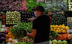 A man wearing a face mask as a preventive measure against the spread of the new coronavirus, COVID-19, buys groceries at a municipal market in Caracas, on March 20, 2020.