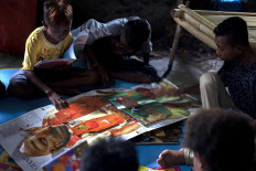 Children read a pop-up book during a literacy event in Waiwuring, East Flores. JP/ Yusuf Wahil