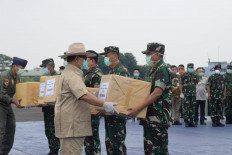 Defense Minister Prabowo Subianto (left) hands over to local military officers medical supplies from China that will be used in efforts to contain the COVID-19 outbreak in Indonesia on March 23 at the Halim Perdana Kusuma Air Force Base in Jakarta.