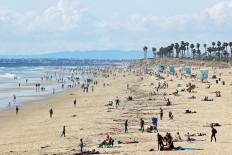 People are seen on the beach on March 21, 2020 in Huntington Beach, California. 