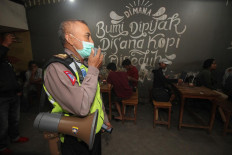 A police officer urges residents to leave a cafe in Surabaya, East Java, on Monday in an effort to curb the spread of COVID-19. 