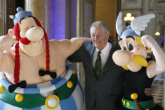 In this file photo taken on March 25, 2015 French cartoon artist Albert Uderzo poses with people dressed as Asterix (R) and Obelix during a press conference at the Monnaie de Paris where a new series of twelve coins illustrated with Asterix designs entitled 'Asterix and the values of the Republic' was presented. 