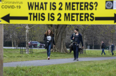 A sign notifies passers by of the 2 meter social distancing measures in place, as people exercise in Phoenix Park in Dublin, on March 25, 2020, after Ireland introduced measures to help slow the spread of the novel coronavirus.Ireland will ease quarantine restrictions on people travelling from abroad on July 20, with people arriving from a "green list" of countries with low COVID-19 rates to be exempt from isolating themselves for 14 days, transport minister Eamon Ryan said.
