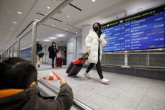 Travelers are seen wearing masks at the international arrivals area at the Toronto Pearson Airport in Toronto, Canada, on January 26, 2020. 