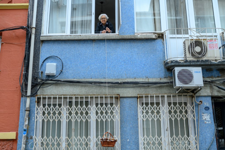 Lutfiye Yesilbas, 89-year-old Turkish woman who lives alone in her home, lowers down her basket as her neighbor (not pictured) wait to take it at Kadikoy, in Istanbul, on March 23, 2020. 