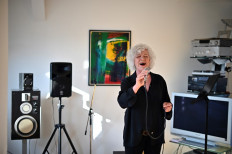 German resident of an 'artists' colony' Ingrid Ihnen-Haas performs a song by Edith Piaf in her flat in south-west Berlin on March 24, 2020 as part of a collective effort to help entertain a country confined to their homes by the coronavirus pandemic. 