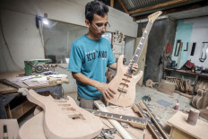 A man works on a guitar at the Arya Guitar Custom workshop in Klapanunggal, Bogor, West Java, on March 28, 2020. 