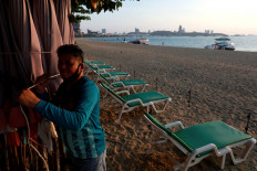 A man collects his umbrellas on an almost empty beach which was usually crowded with tourists following the coronavirus disease (COVID-19) outbreak in Pattaya, Thailand, on March 27, 2020. 