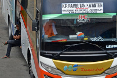 A bus crew member waits for passengers at Kampung Rambutation Station in Jakarta on Monday.
