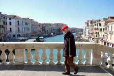 A man wearing a protective mask on an empty Rialto Bridge on Sunday with an unprecedented lockdown across of all Italy imposed to slow the outbreak of coronavirus, in Venice, Italy, on March 15, 2020. 