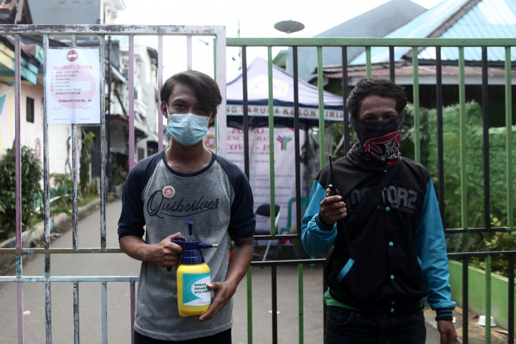 Residents of Kalipasir, Central Jakarta, Spray disinfectant on another resident motorcycle before entering the residential area in Jakarta, Tuesday, March 31, 2020.