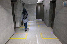 Taped off areas to demarcate distances between people are seen in the lift lobby of an office building in Singapore on March 31, 2020, as authorities implement social distancing measures as a preventive measure against the spread of the COVID-19 novel coronavirus. 