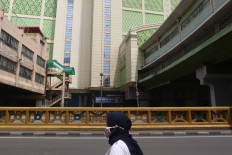 A resident wearing a mask passes in front of Tanah Abang Market in Jakarta on April 1, 2020. 