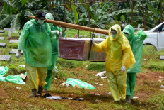 Workers carry a coffin of a victim of the COVID-19 coronavirus during a funeral in Jakarta on March 31, 2020. 