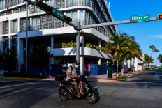 A delivery man rides a scooter wearing a mask amid fears over the spread of the novel coronavirus (COVID-19) in South Beach in Miami, on March 31, 2020. 