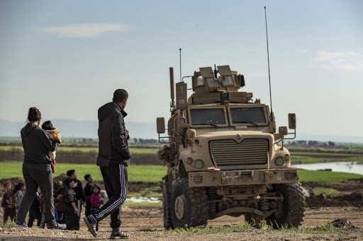 A man walks past a US military vehicle on patrol along the M4 motorway near Hasakah in the countryside of Syria's northeastern province of Hasakah on April 3, 2020. Israel will keep up its operations in Syria until its arch enemy Iran leaves, Defense Minister Naftali Bennett said Tuesday after strikes on Iranian-backed militias and their allies killed 14 fighters.