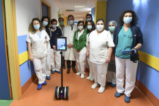 Members of medical staff and the director of infectious diseases department, Paolo Grossi (center), pose with a robot called Ivo used to help patients infected by the novel coronavirus, on April 3, 2020 at the Circolo di Varese hospital, amid the the spread of the epidemic COVID-19.