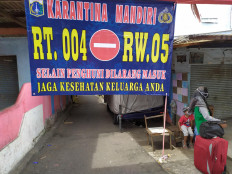 A banner declaring self-quarantine measures put in place by residents is seen in front of a neighborhood in Halim Perdanakusuma, East Java, on Monday. Residents have urged people not to pass through the area or visit their homes in an attempt to prevent the further transmission of COVID-19.