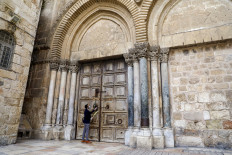 A worshiper prays outside the closed door of the Holy Sepulchre Church during Palm Sunday in Jerusalem's Old City amid movement restrictions due to the COVID-19 coronavirus pandemic, on April 5 2020.

