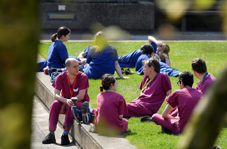 Medical staff take a break in the grounds of St Thomas' Hospital as the spread of the coronavirus disease (COVID-19) continues, London, Britain, April 10, 2020. 