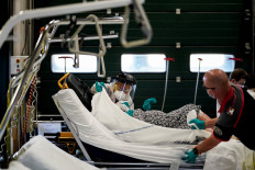 A Belgian first-aid firefman wearing personal protection equipment (PPE) speaks to a patient on a gurney, suspected of being infected with COVID-19, as they arrive at hospital in Liege on April 10, 2020. 