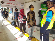 An officer checks the body temperature of commuter line train passengers at Depok Station in Depok, West Java, on April 13.