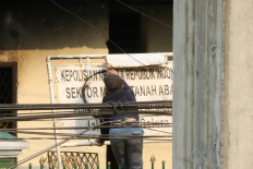 A man writes graffiti on the signpost of a police station next to the House of Representatives building in Senayan, Central Jakarta on Sept. 25, 2019.